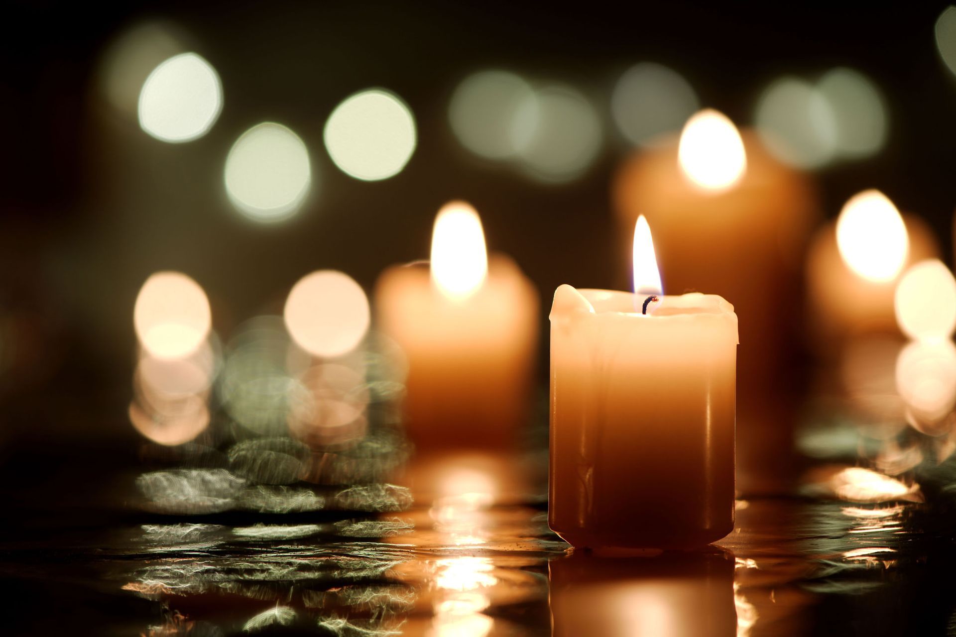 A group of lit candles are reflected in the water.