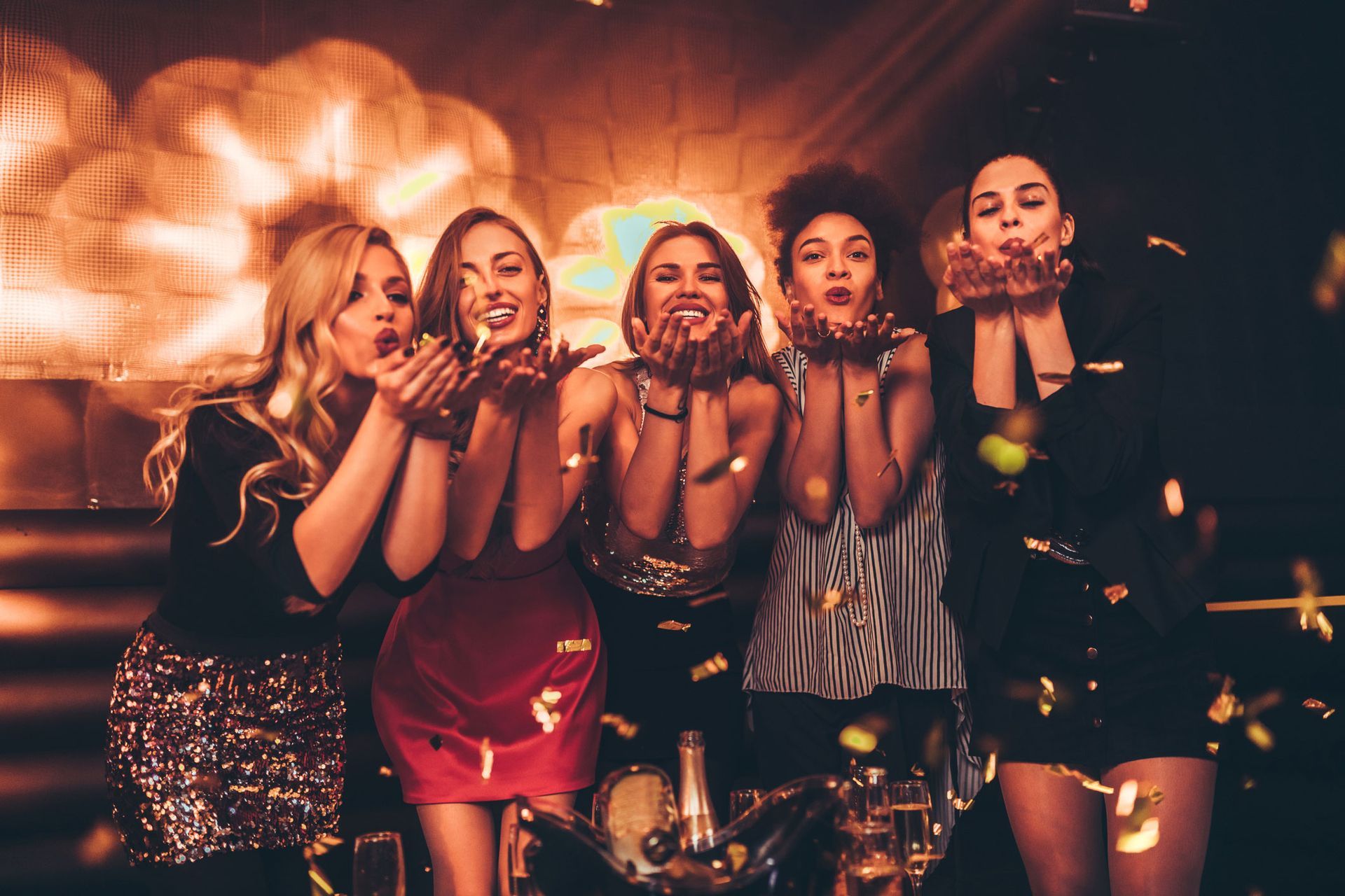 A group of women are blowing confetti at a party.