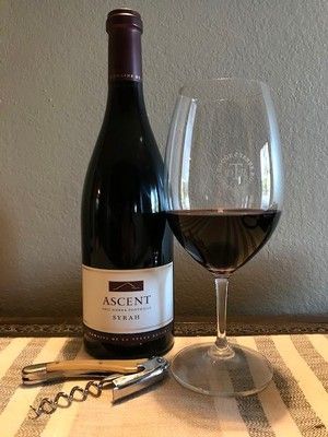 A bottle of wine and a glass of wine are on a table.