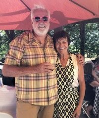 A man and a woman are posing for a picture under an umbrella.