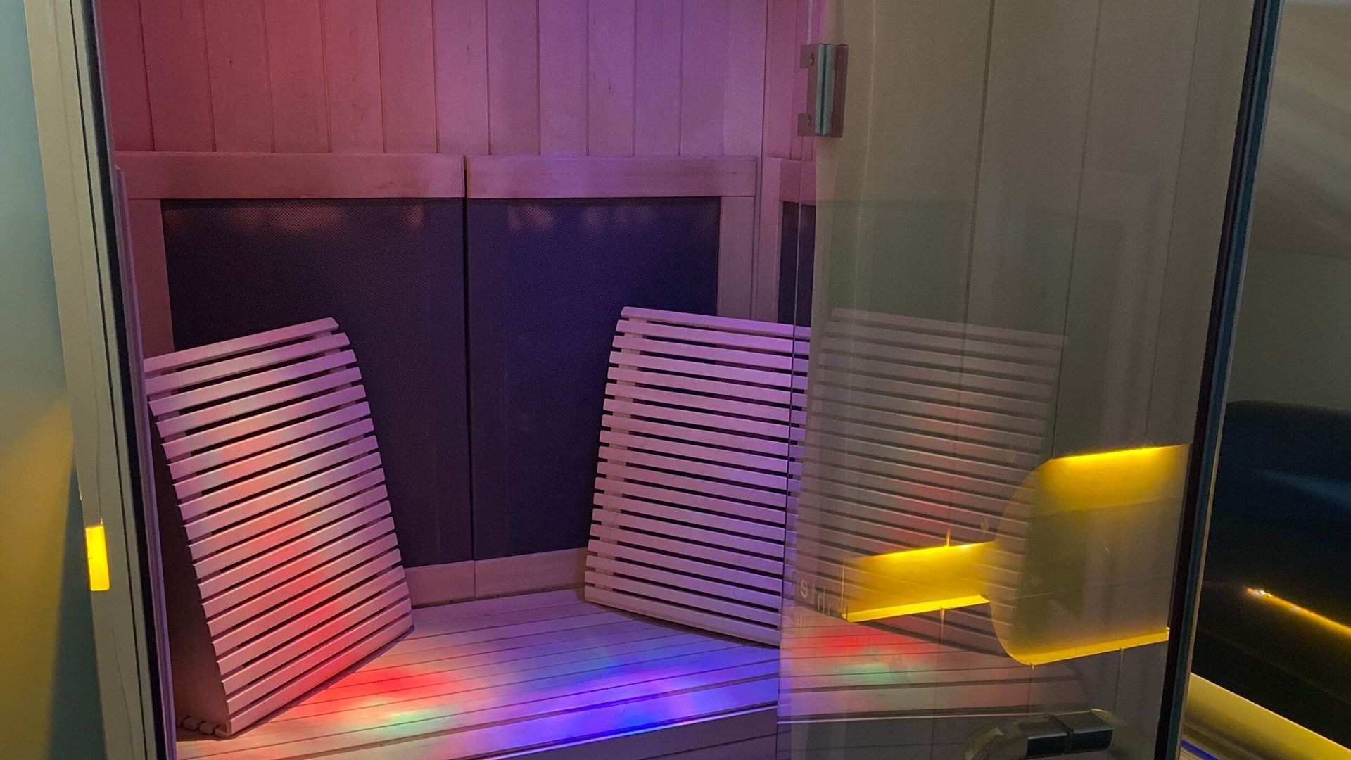 A sauna with a lot of lights on it and a glass door.