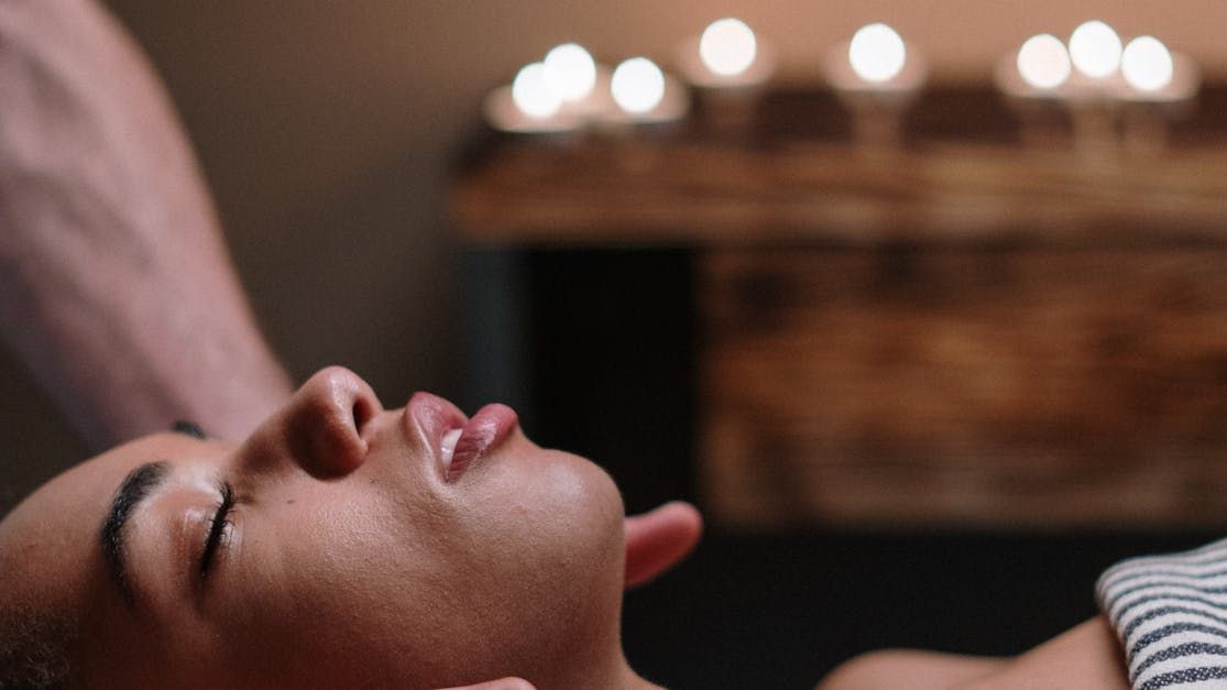 A man is giving a woman a massage with her eyes closed.