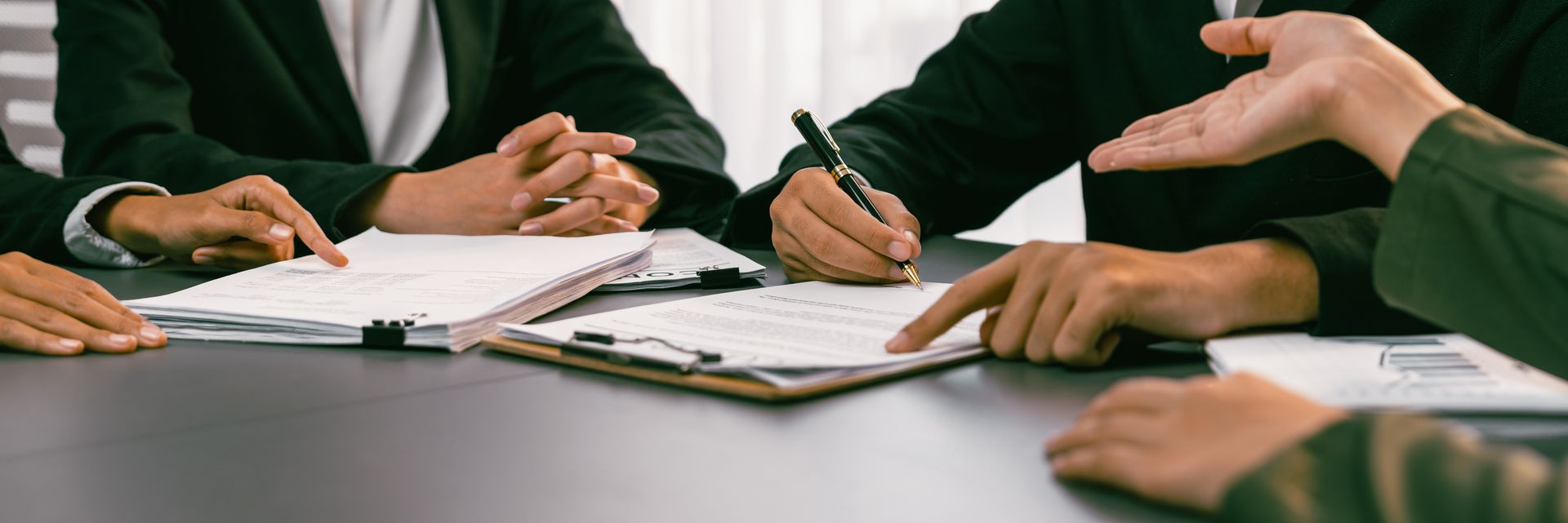 A group of people are sitting around a table signing papers.