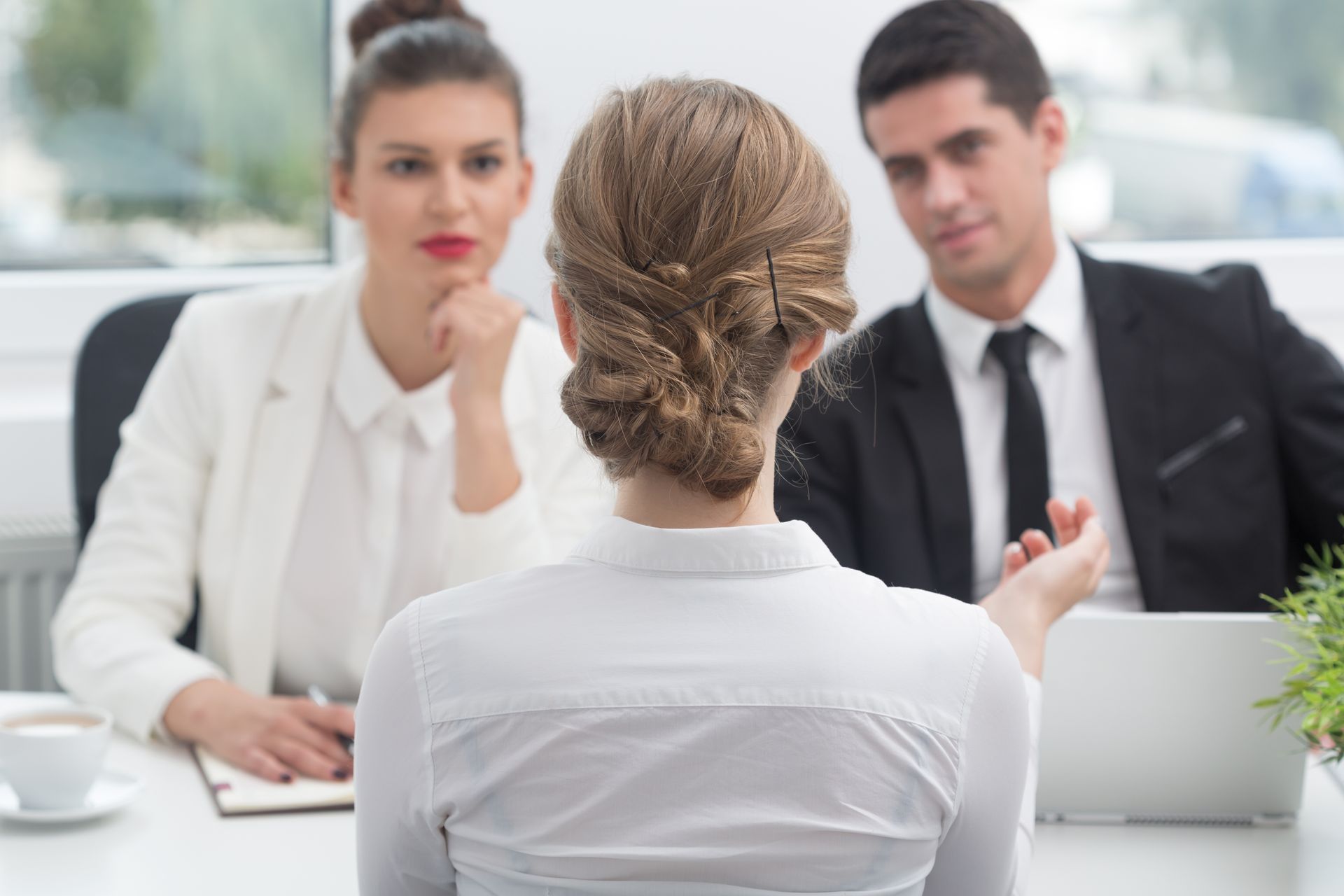 A woman is sitting at a table during a job interview.