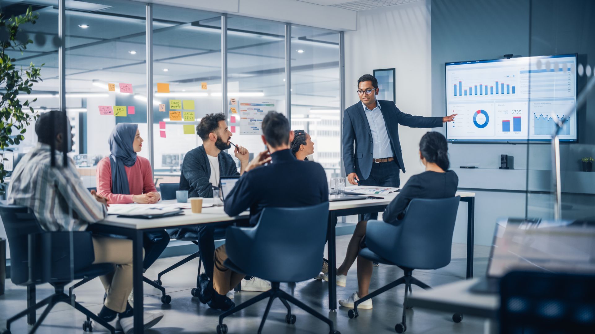 A man is giving a presentation to a group of people sitting around a table.