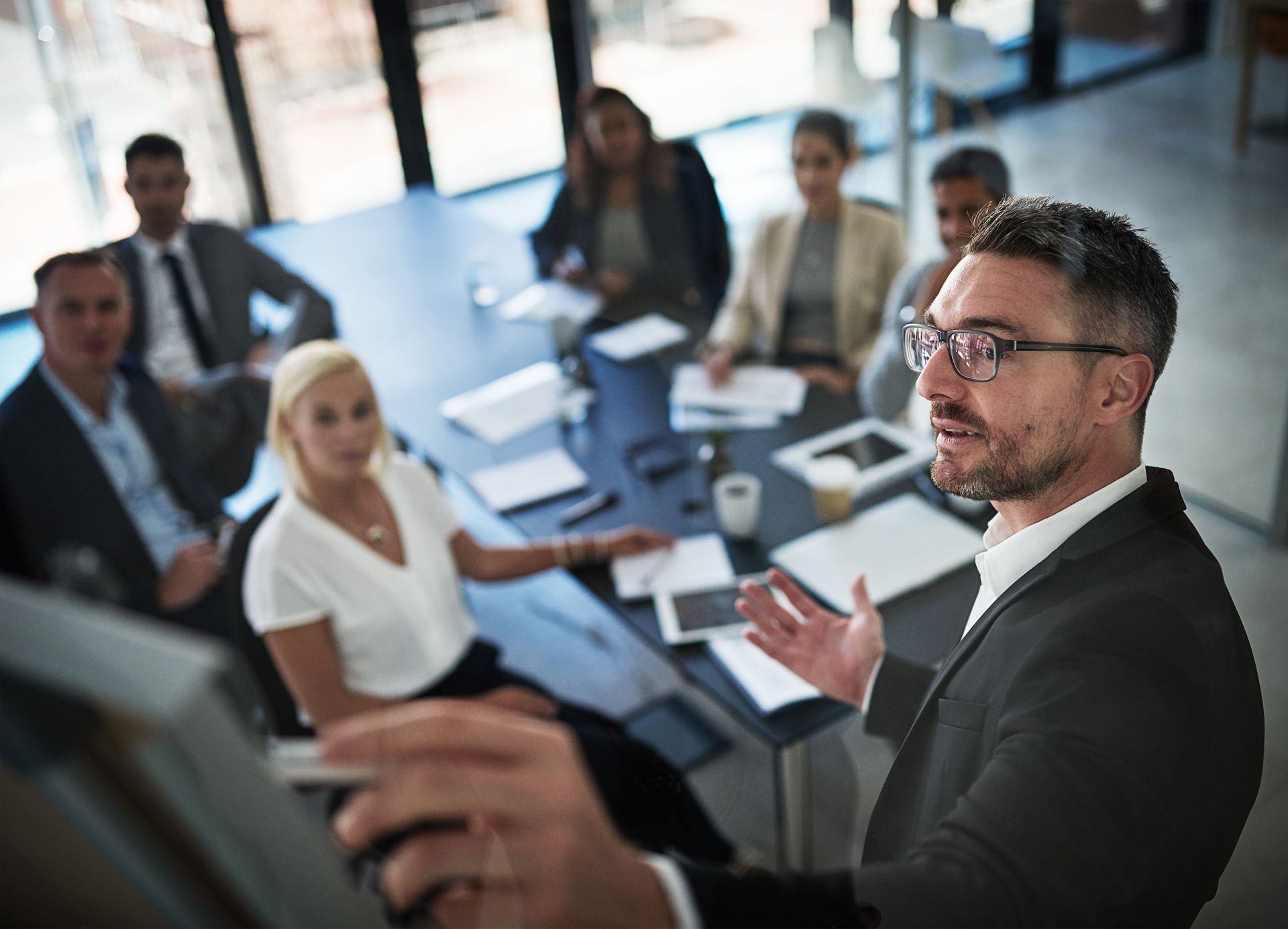 A man is giving a presentation to a group of people sitting around a table.