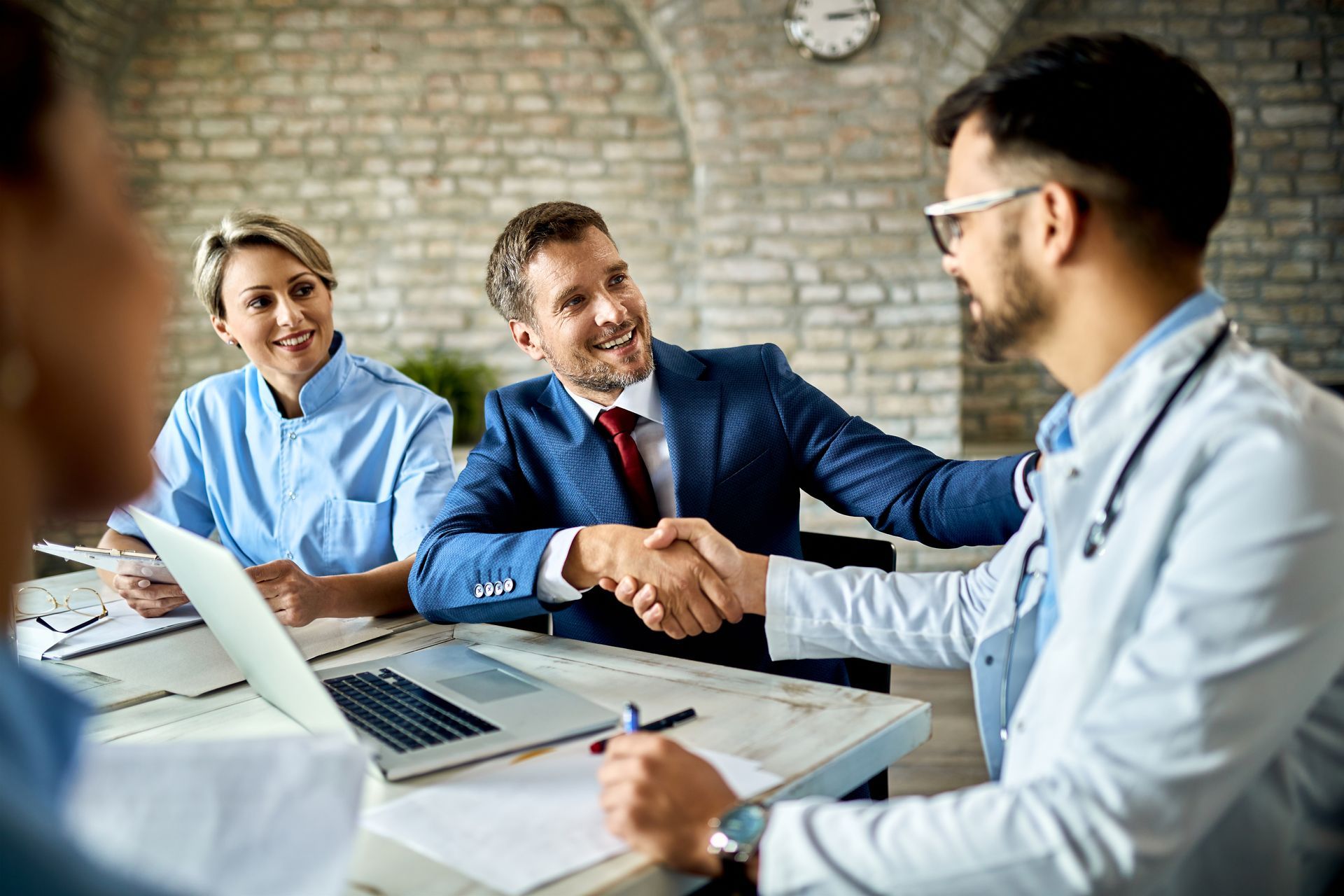 A doctor is shaking hands with a businessman during a meeting.