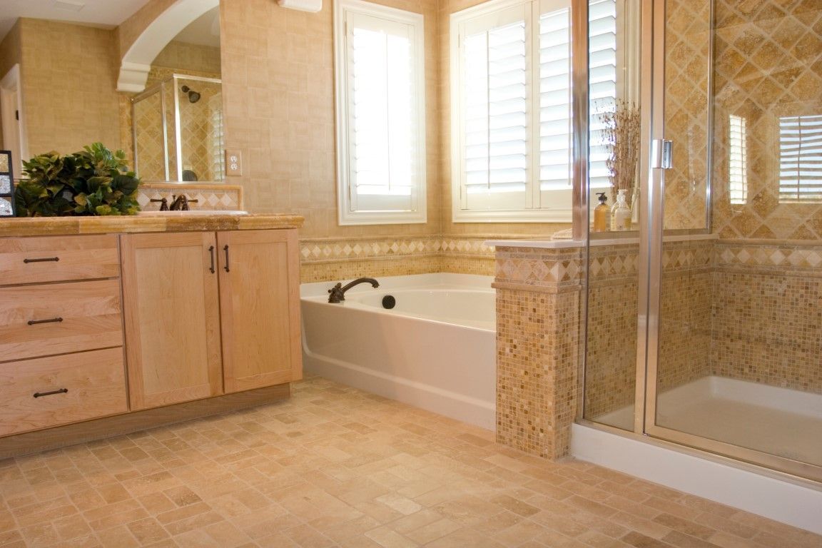 Bathroom with beige tile, wooden vanity, bathtub, and shower.