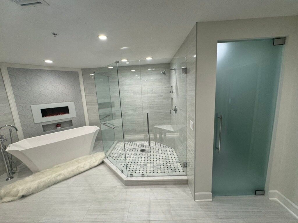 Modern bathroom with a glass shower, soaking tub, and frosted glass door. Light grey and white color scheme.