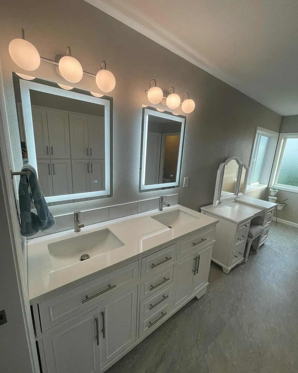 A bathroom with two sinks , two mirrors and a vanity.