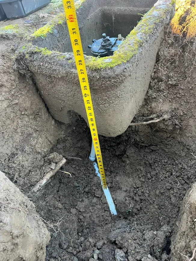 A tape measure is measuring a hole in the ground.