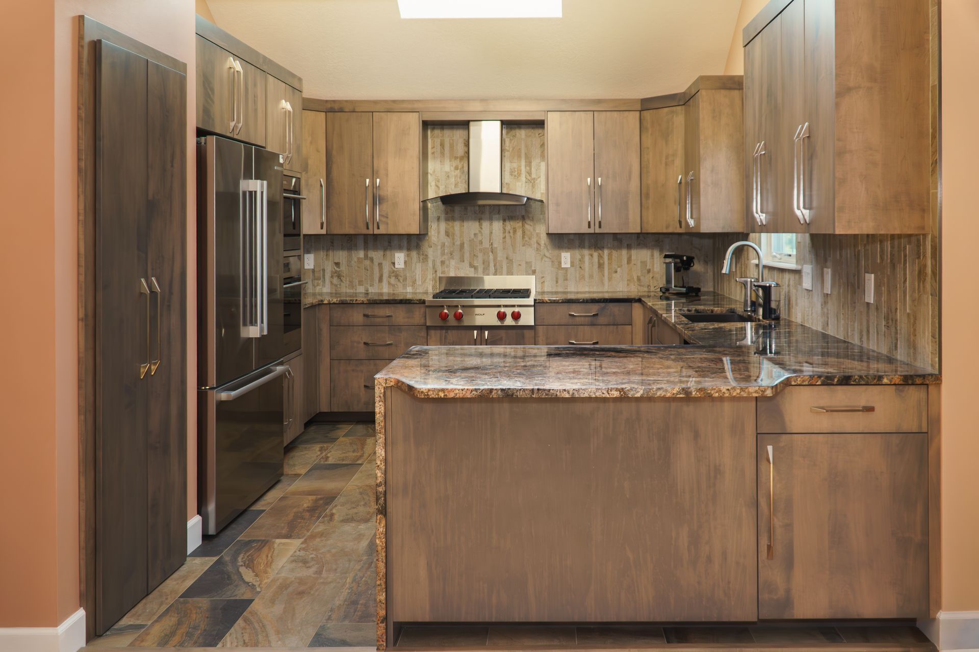 Custom, stained modern frameless wood kitchen cabinets and island, stainless appliances and range hood.