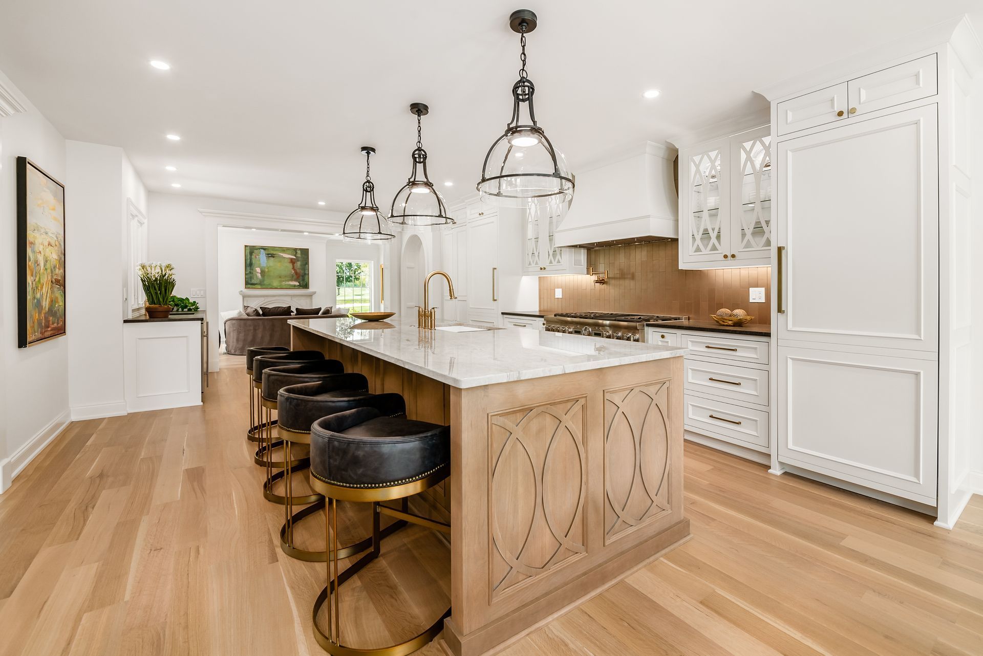 Custom white painted wood kitchen cabinets and carved stained wood island with beautiful pendant lights.