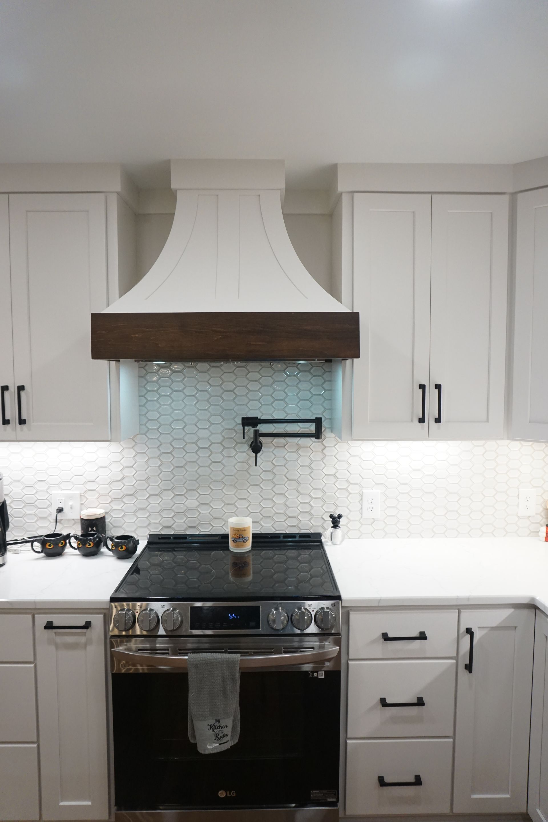 Custom white painted and stained wood range hood with curved sides.
