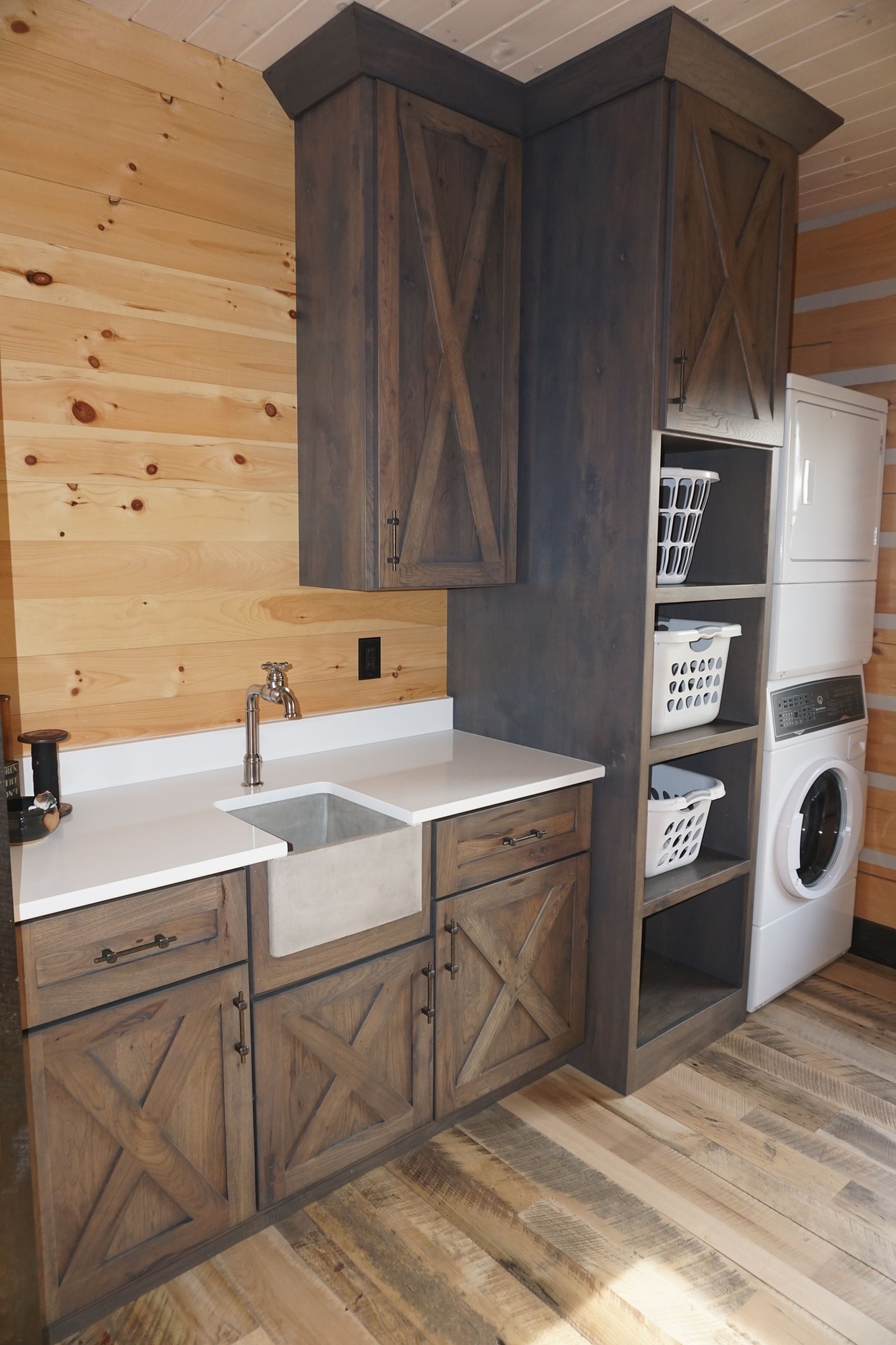 Custom stained wood X braced wood laundry cabinets with farmhouse sink.