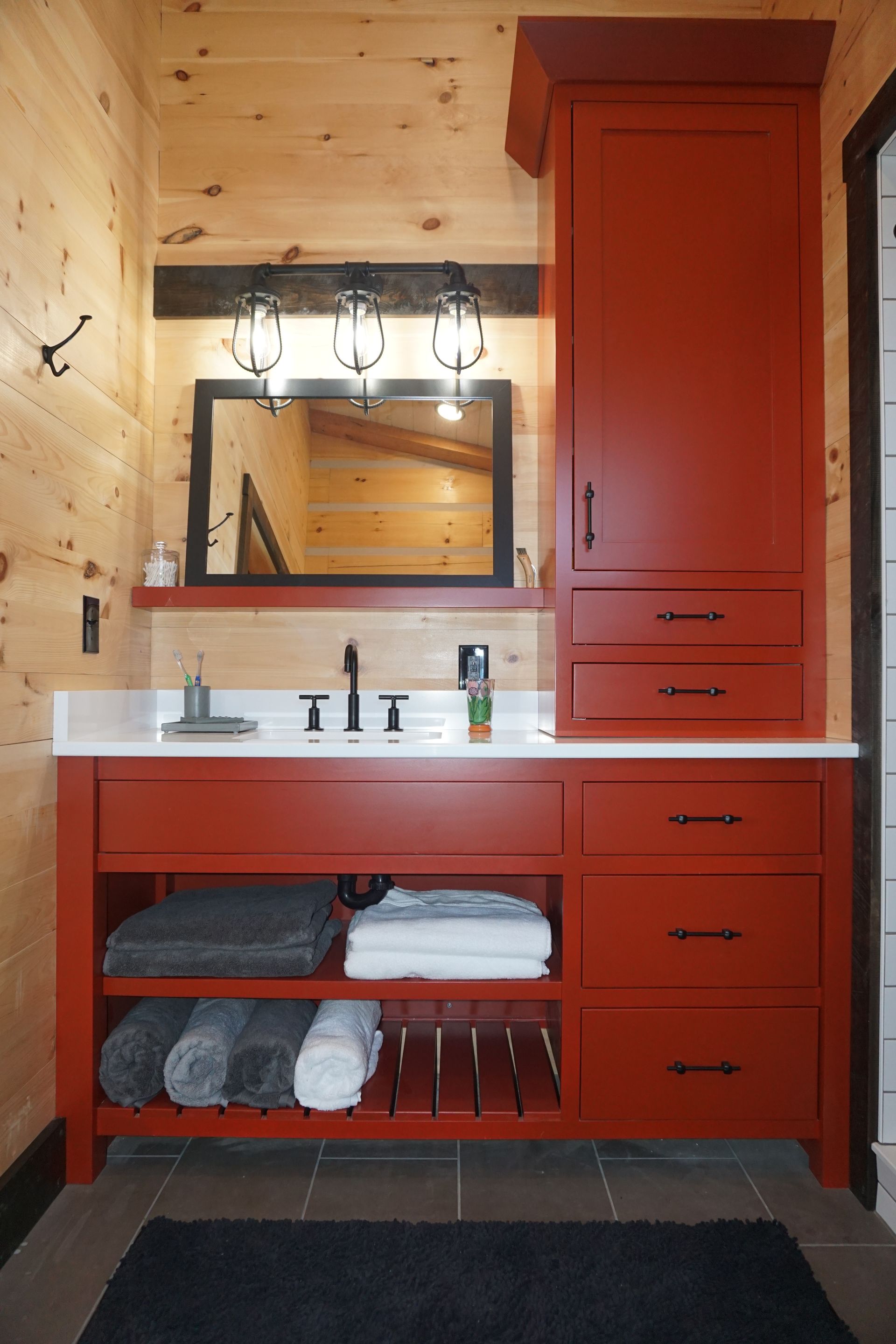 Custom red painted wood bathroom vanity and tower with inset doors and drawers for a modern look.