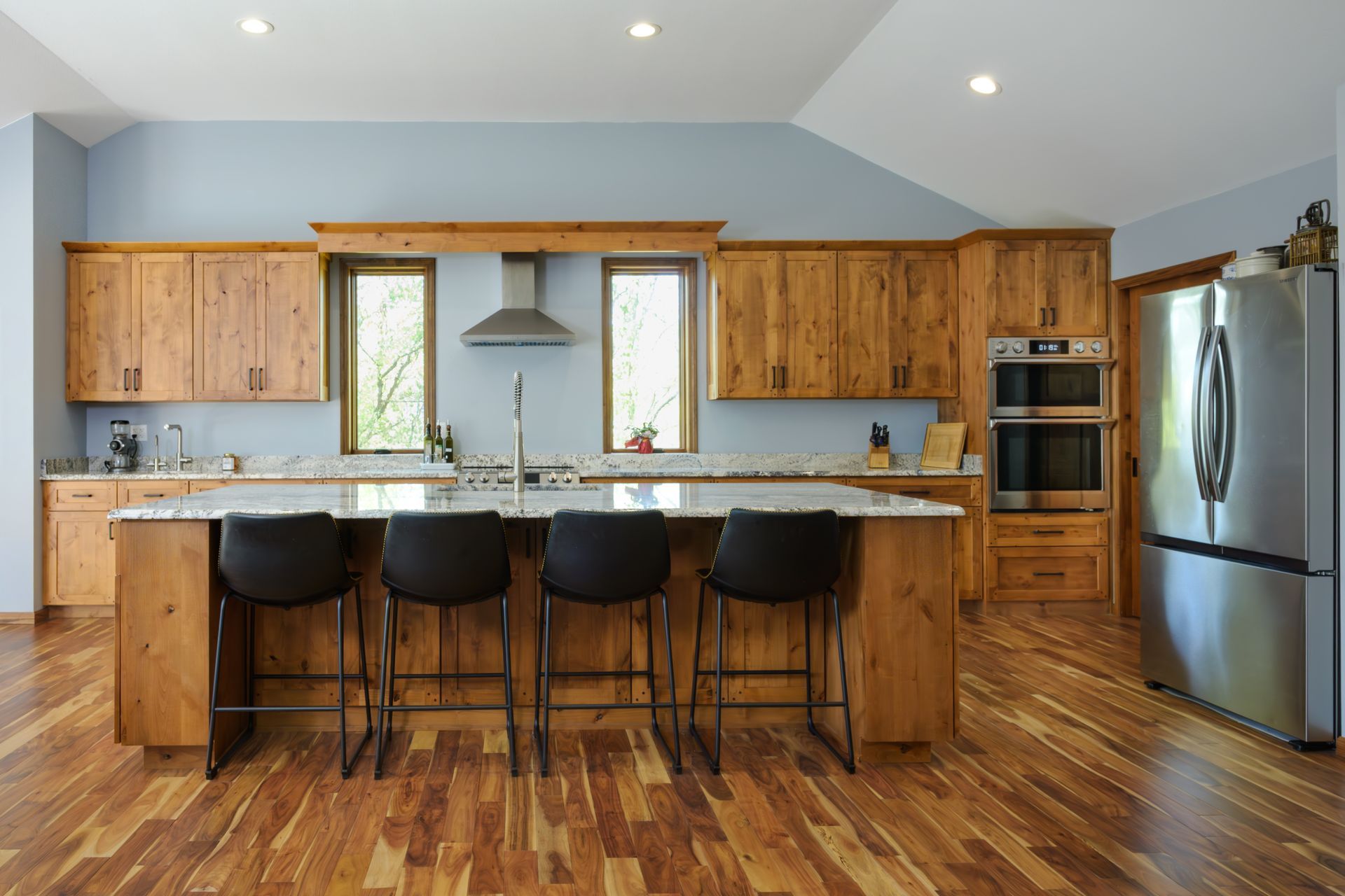 Custom, stained modern wood kitchen cabinets and island, stainless appliances and range hood.