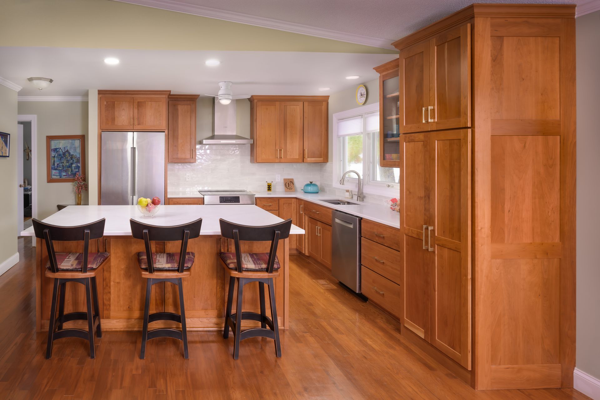 Custom, stained cherry wood kitchen cabinets and island, stainless appliances and range hood.