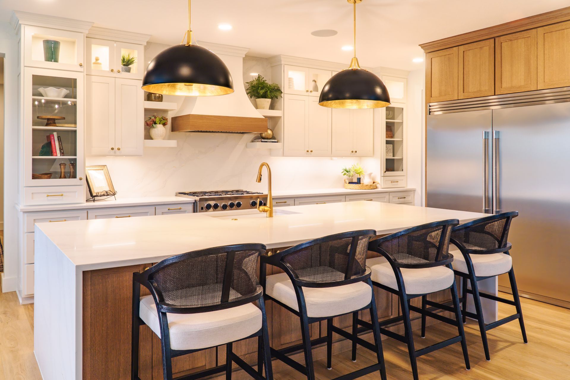 Custom, modern painted kitchen cabinets and stained wood island with waterfall style quartz countertop and pendant lights.