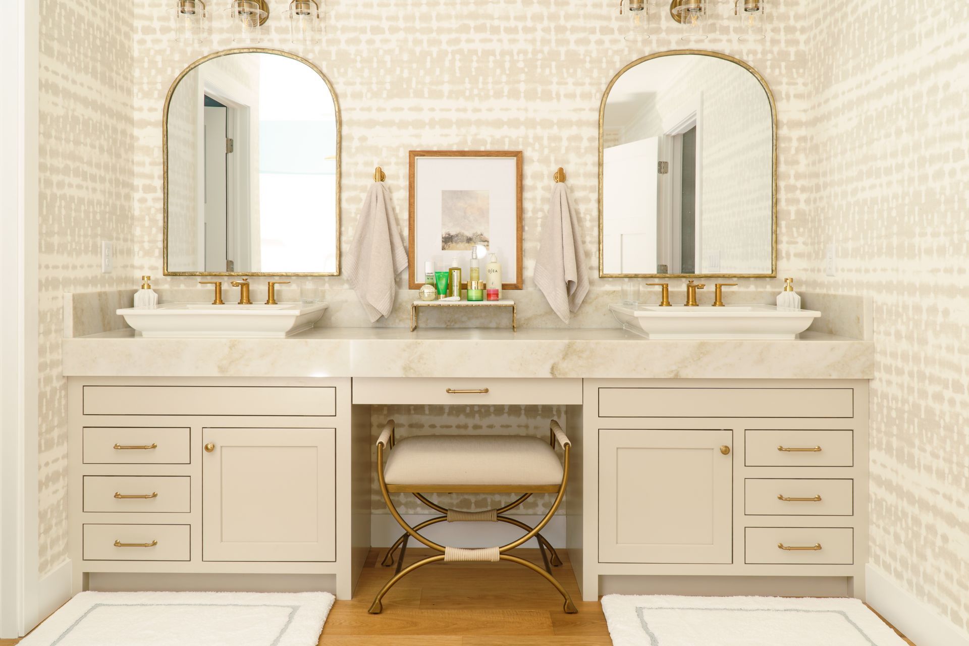 Blue double vanity with tall storage cabinet and oval mirrors in a white bathroom, lit by pendant lights.