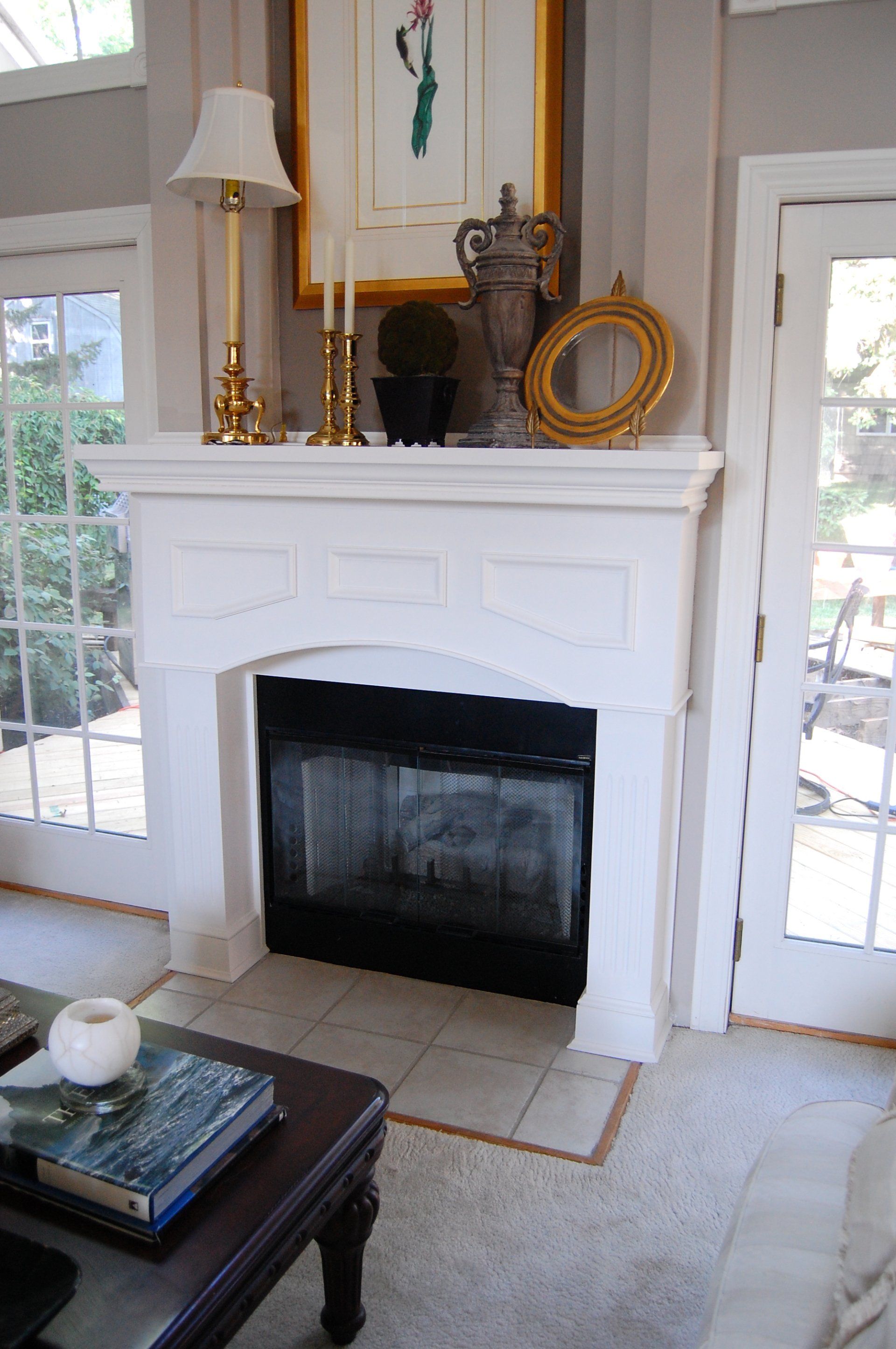 Custom white painted wood fireplace mantel and surround with arched opening.