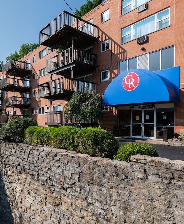 A large brick building with a blue awning with the letter r on it