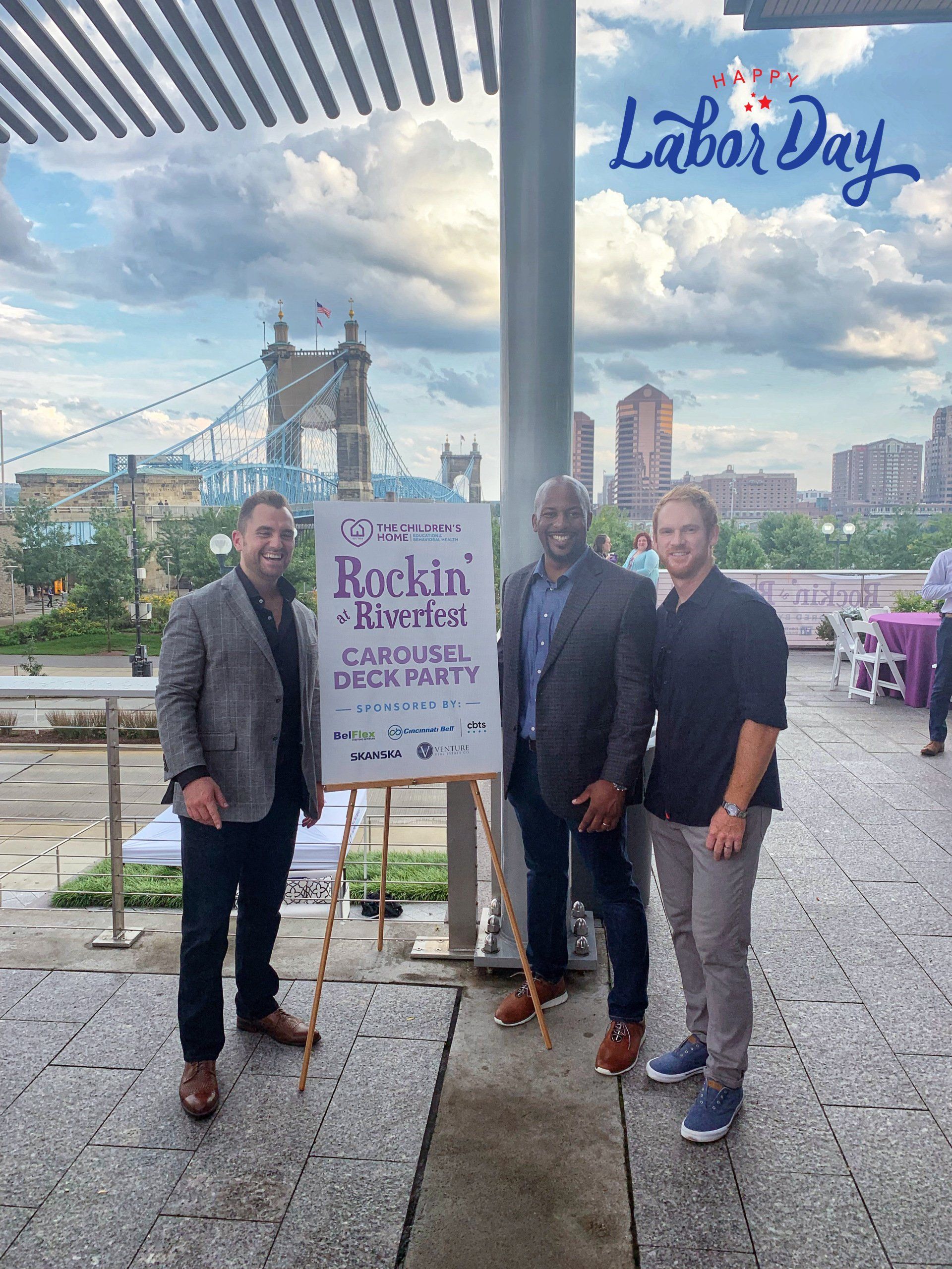 Three men are standing in front of a sign that says labor day.