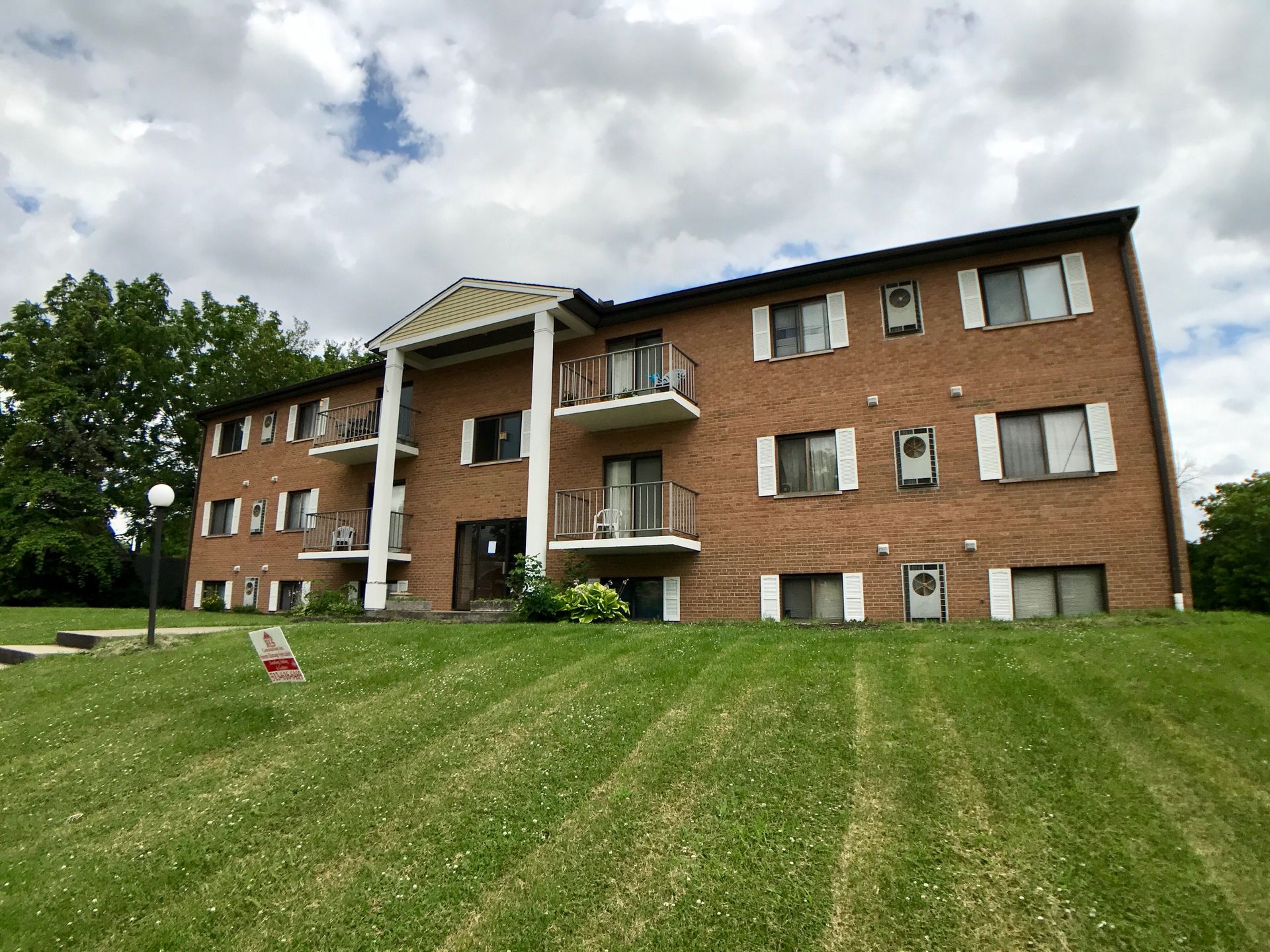 A large brick apartment building with a lush green lawn in front of it