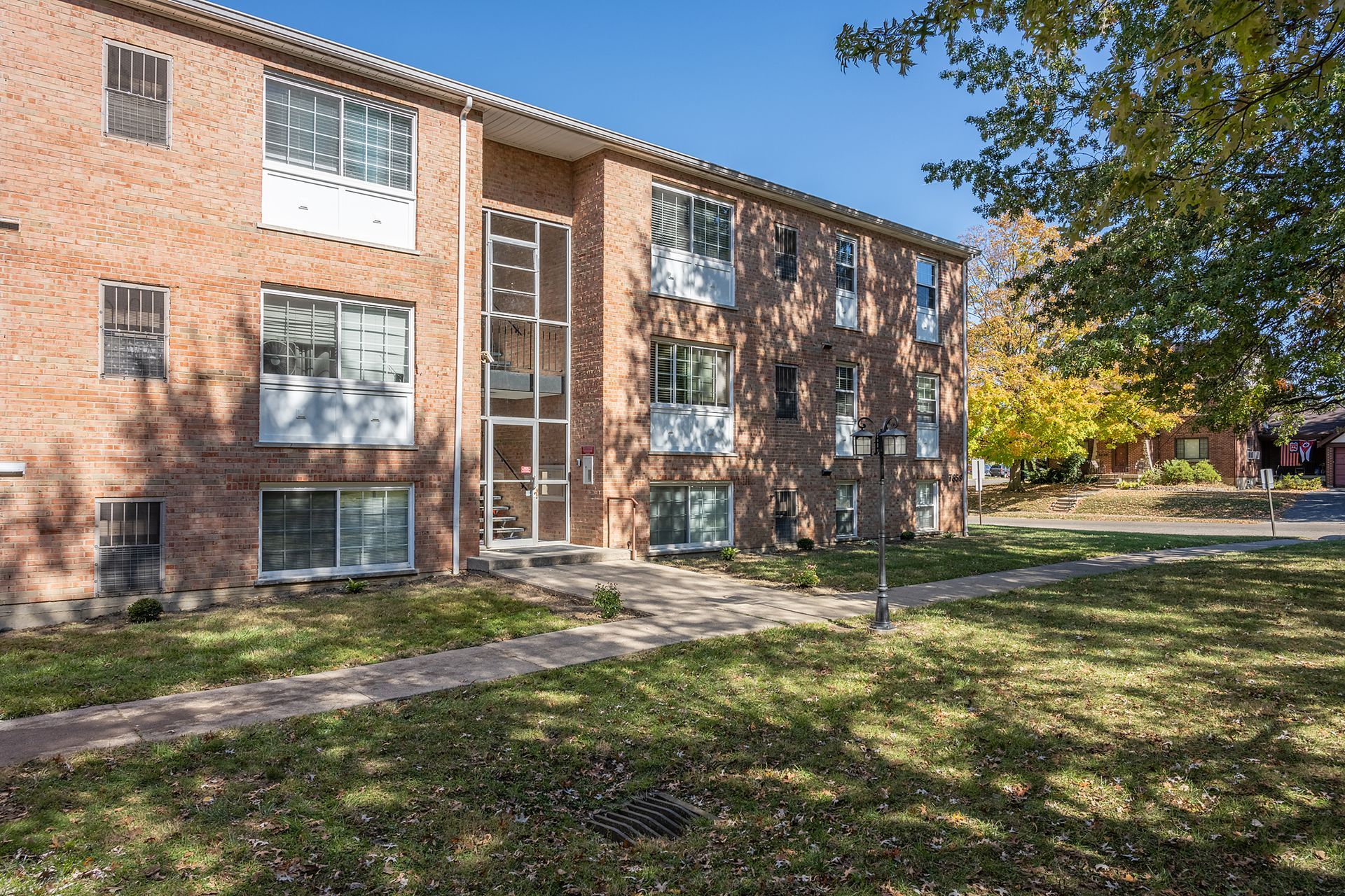 A large brick apartment building with a lush green lawn in front of it.
