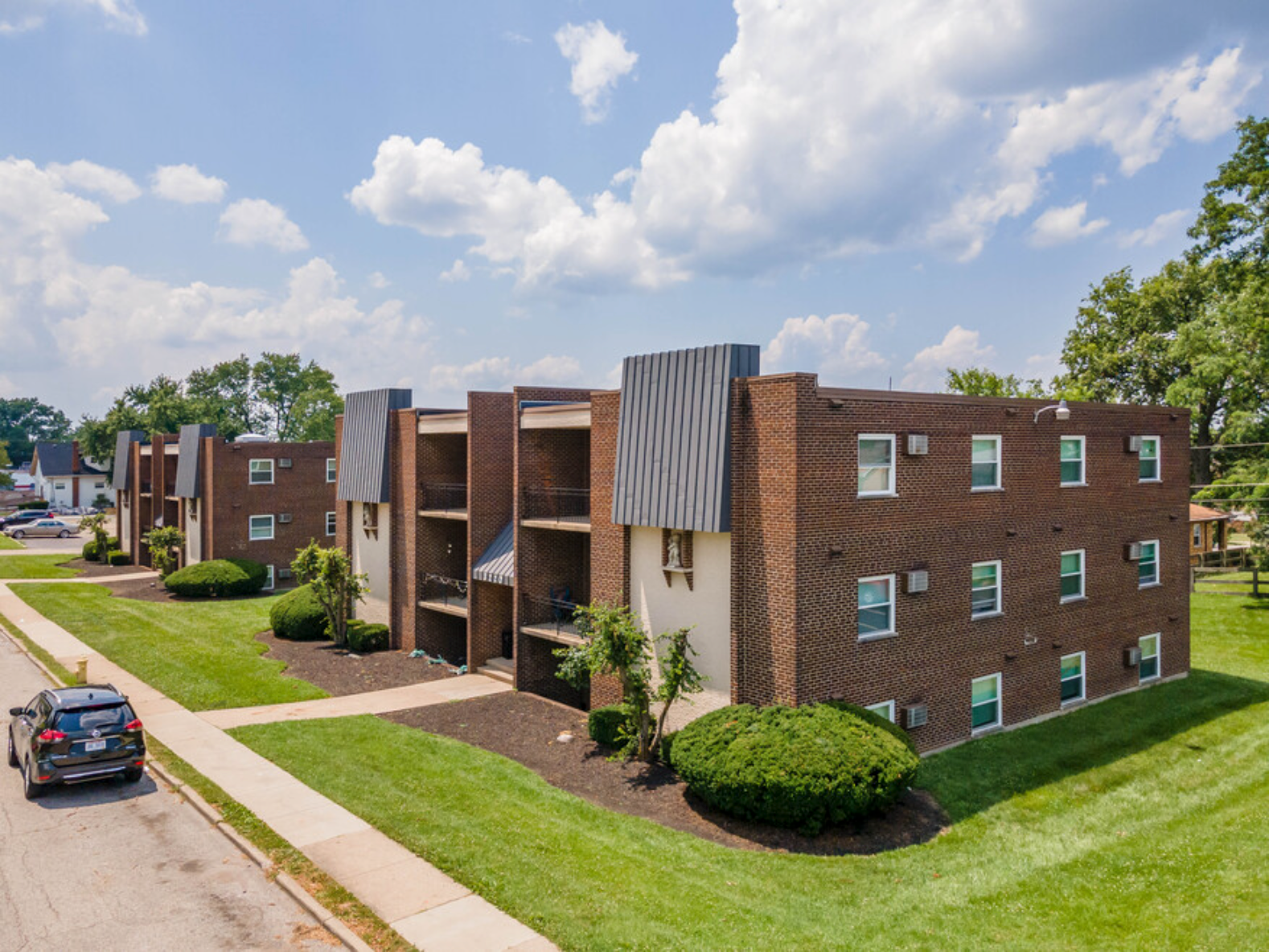 A car is parked in front of a row of apartment buildings.
