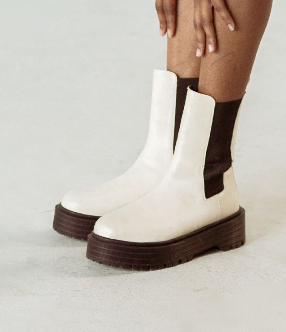 White Chelsea boots with black chunky soles.