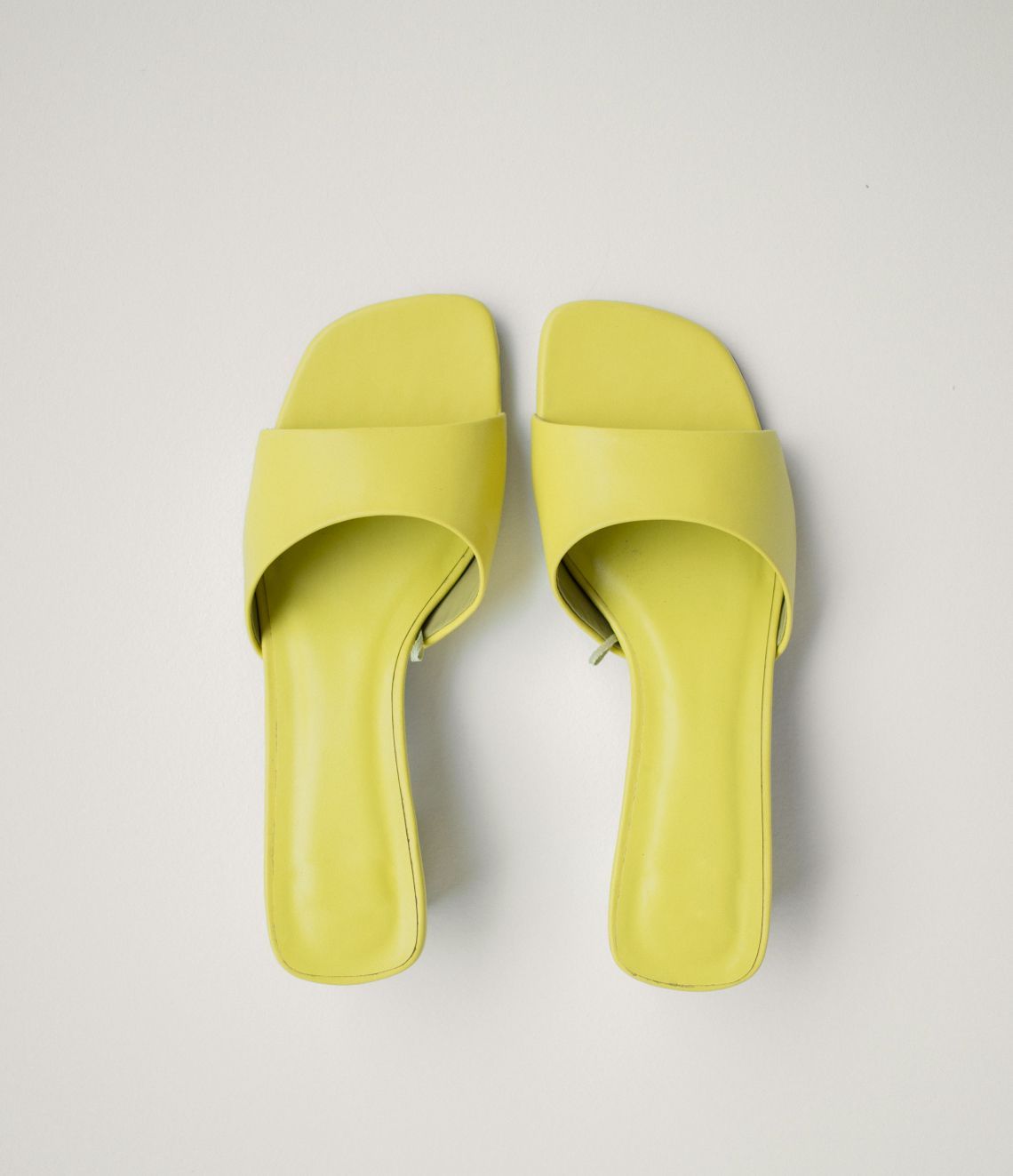 Yellow leather slide sandals on a white background.