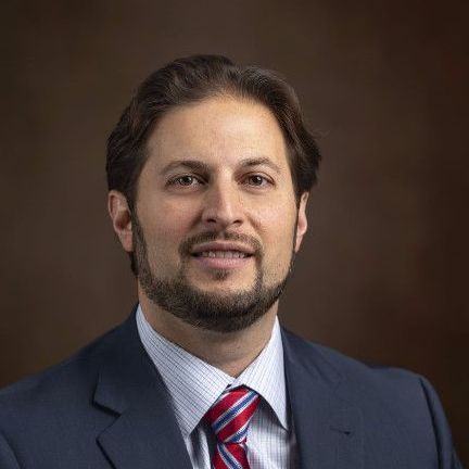 A man with a beard is wearing a suit and tie.