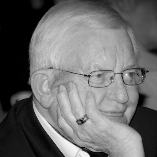 A man in a suit and glasses is holding a trophy.