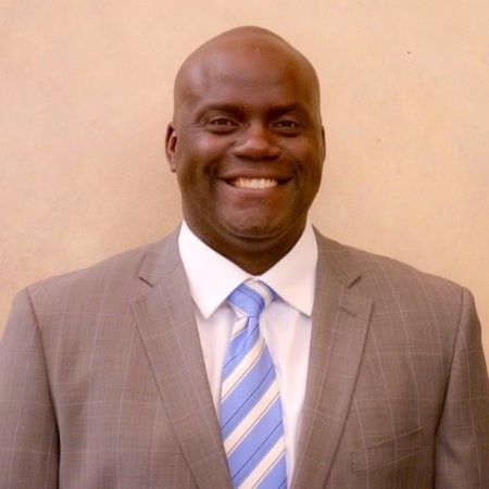 A man in a suit and tie is smiling for the camera