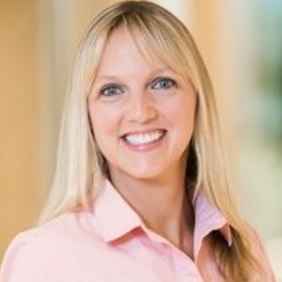 A woman in a pink shirt is smiling for the camera.