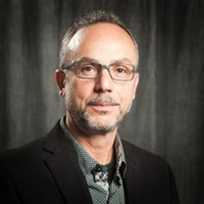 A man with a beard and glasses is wearing a suit and shirt.