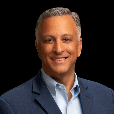 A man in a suit and blue shirt is smiling for the camera.