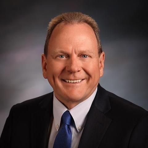 A man in a suit and tie is smiling for the camera.