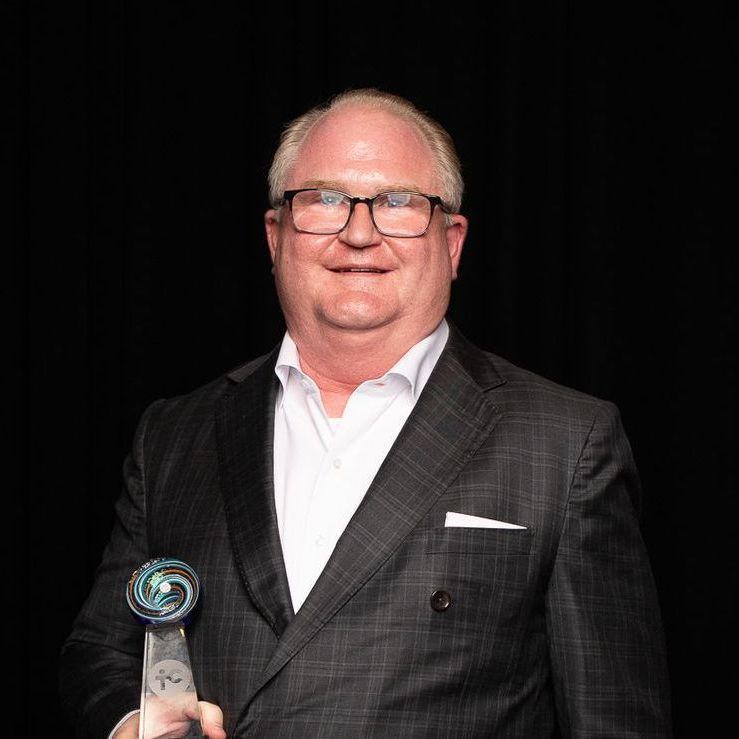 A man in a suit and glasses is holding a trophy.