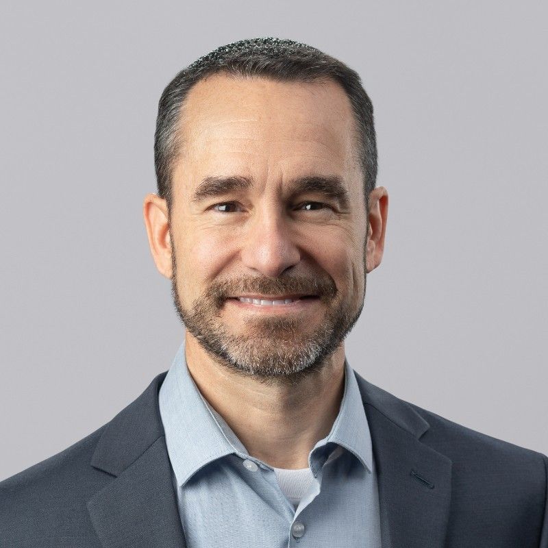 A man with a beard is wearing a suit and smiling for the camera.