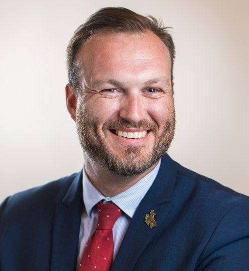 A man with a beard wearing glasses and a blue suit