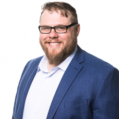 A man with a beard wearing glasses and a blue suit