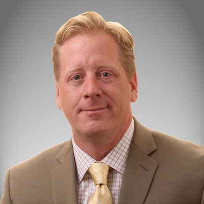 A man in a suit and tie is smiling for the camera.