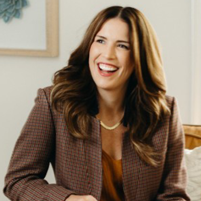 A woman is smiling and wearing a plaid jacket