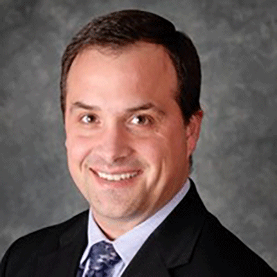 A man in a suit and tie is smiling for the camera.