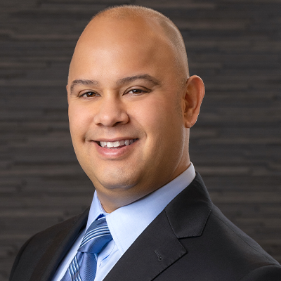 A bald man in a suit and tie is smiling for the camera.