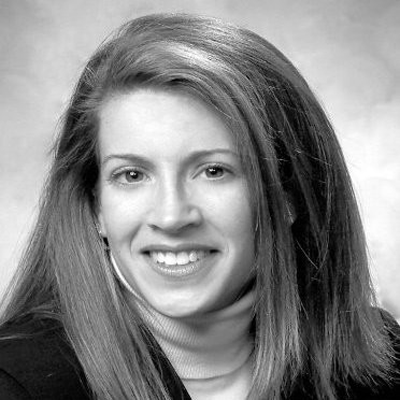 A woman with long hair is smiling in a black and white photo.