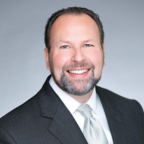 A man in a suit and tie is smiling for the camera.