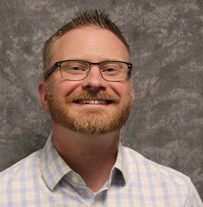 A man with a beard and glasses is smiling for the camera.